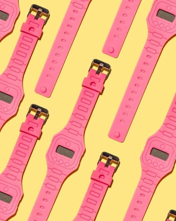 Image of multiple pink casio watches on a yellow background to represent that NotWinging It Leadership club is for those who are already busy and short of time.