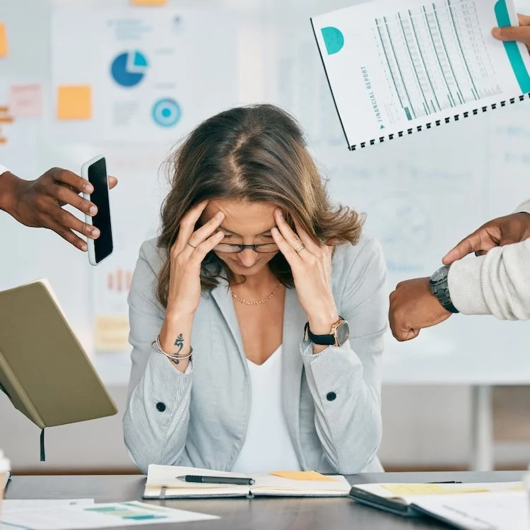 female boss with long brown hair and light grey jacket with head in her hand. she needs some leadership support.