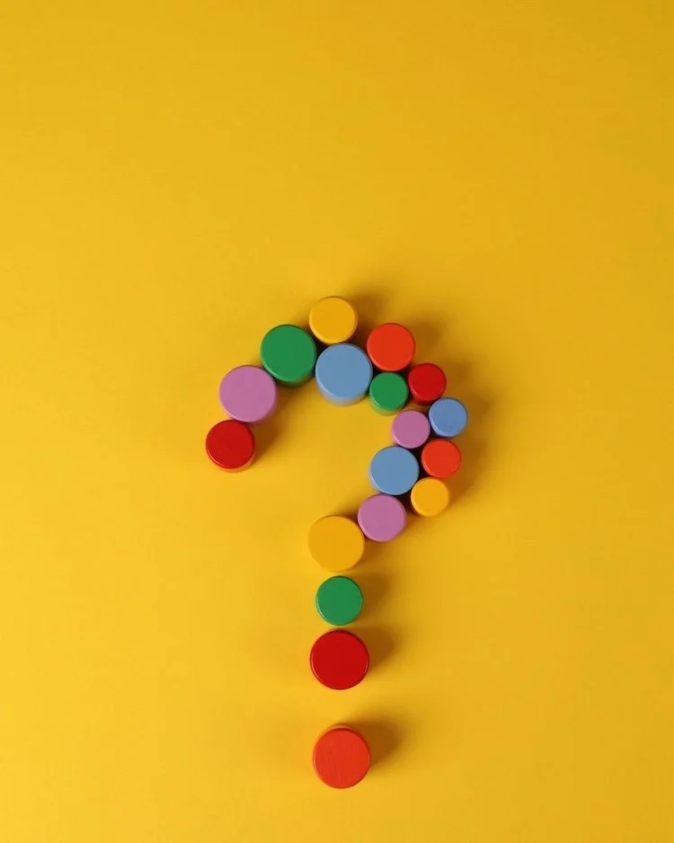 A question mark made from coloured magnets on a yellow background.