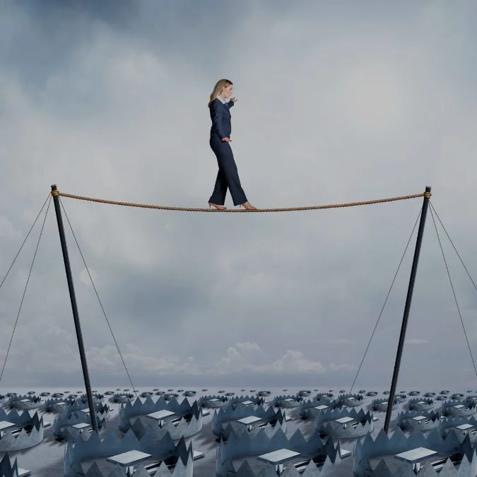 Women with blonde hair wearing a blue trouser suit, walking along a tightrope