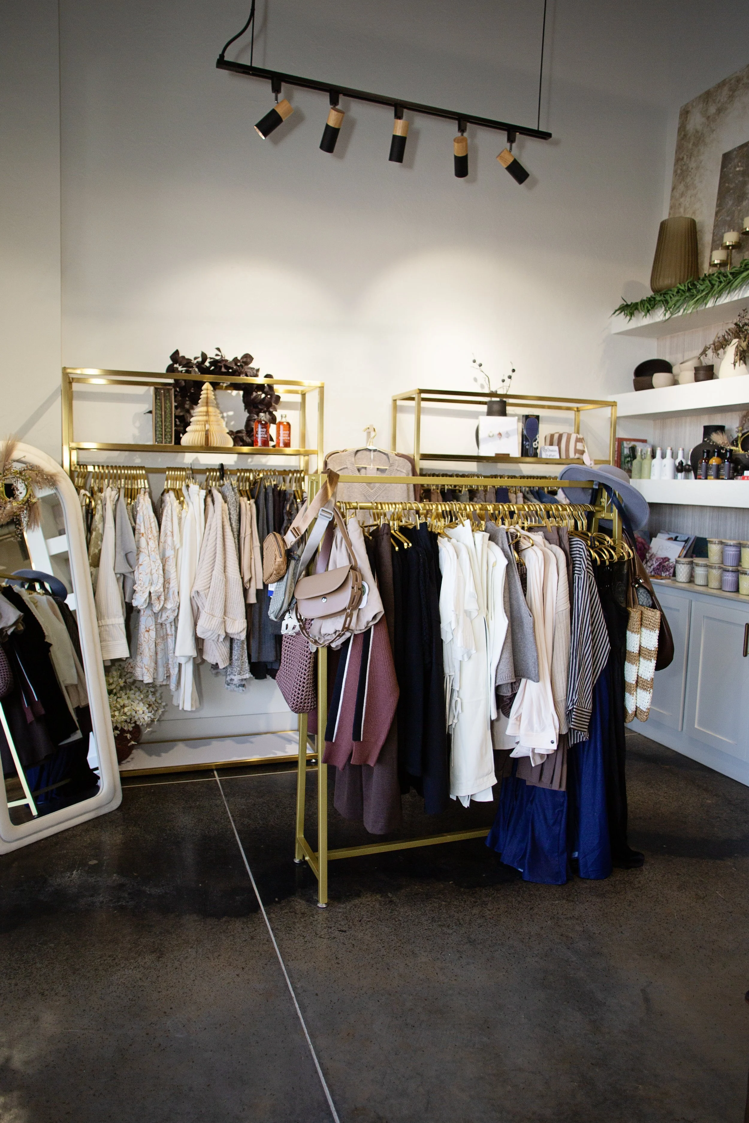 Clothing rack with sweaters and accessories in a boutique store.