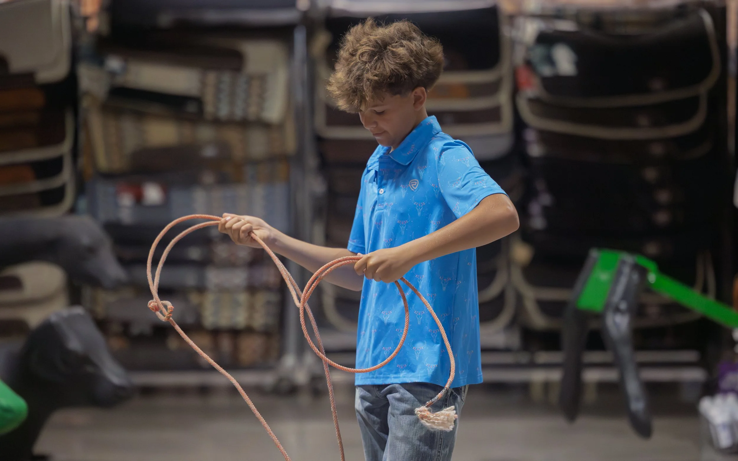 A boy in a blue shirt holding a jump rope, standing in a store aisle with shelves of chairs in the background.