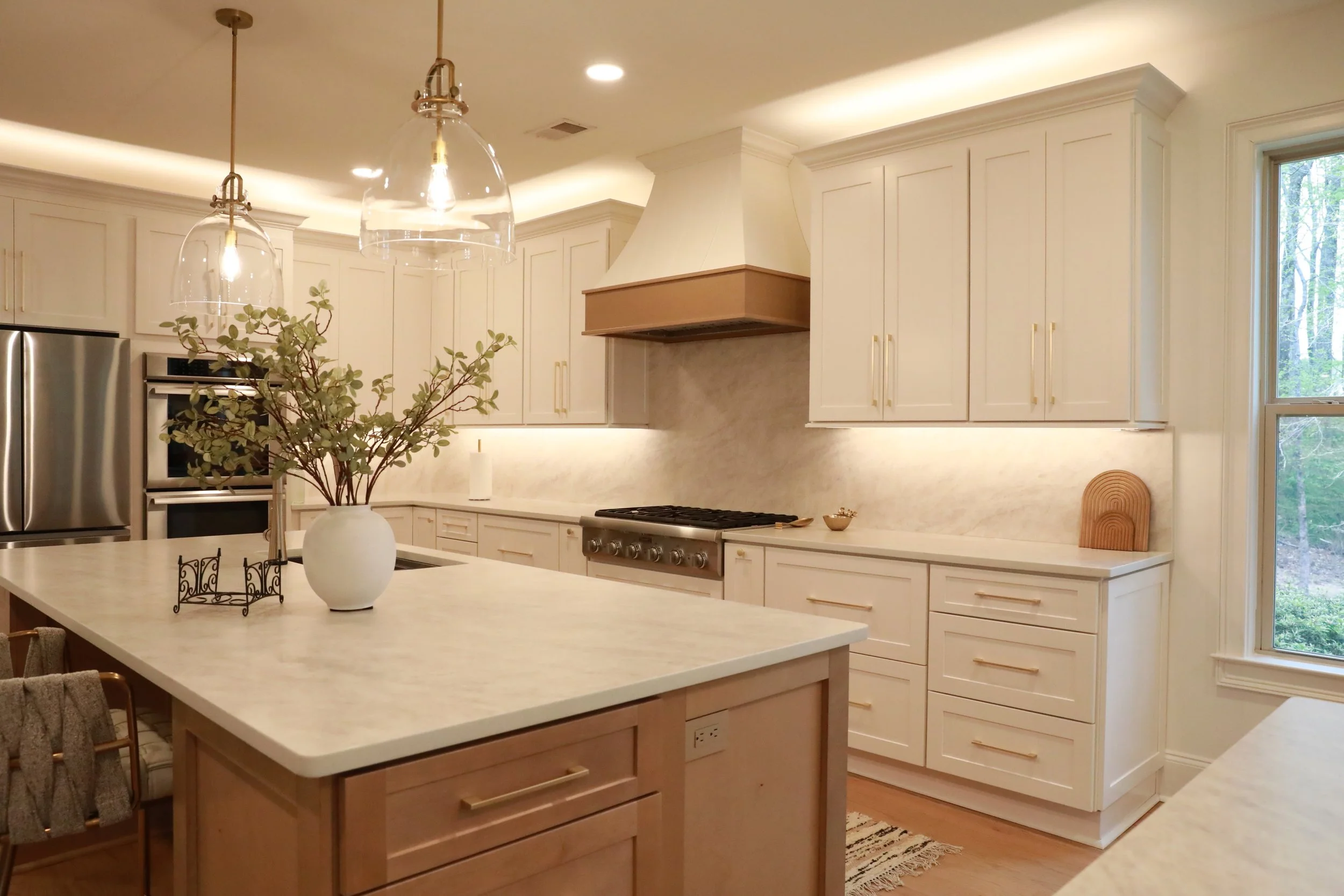 Luxury kitchen remodel in Milton, GA with natural accents, white cabinets, and white marble counters.