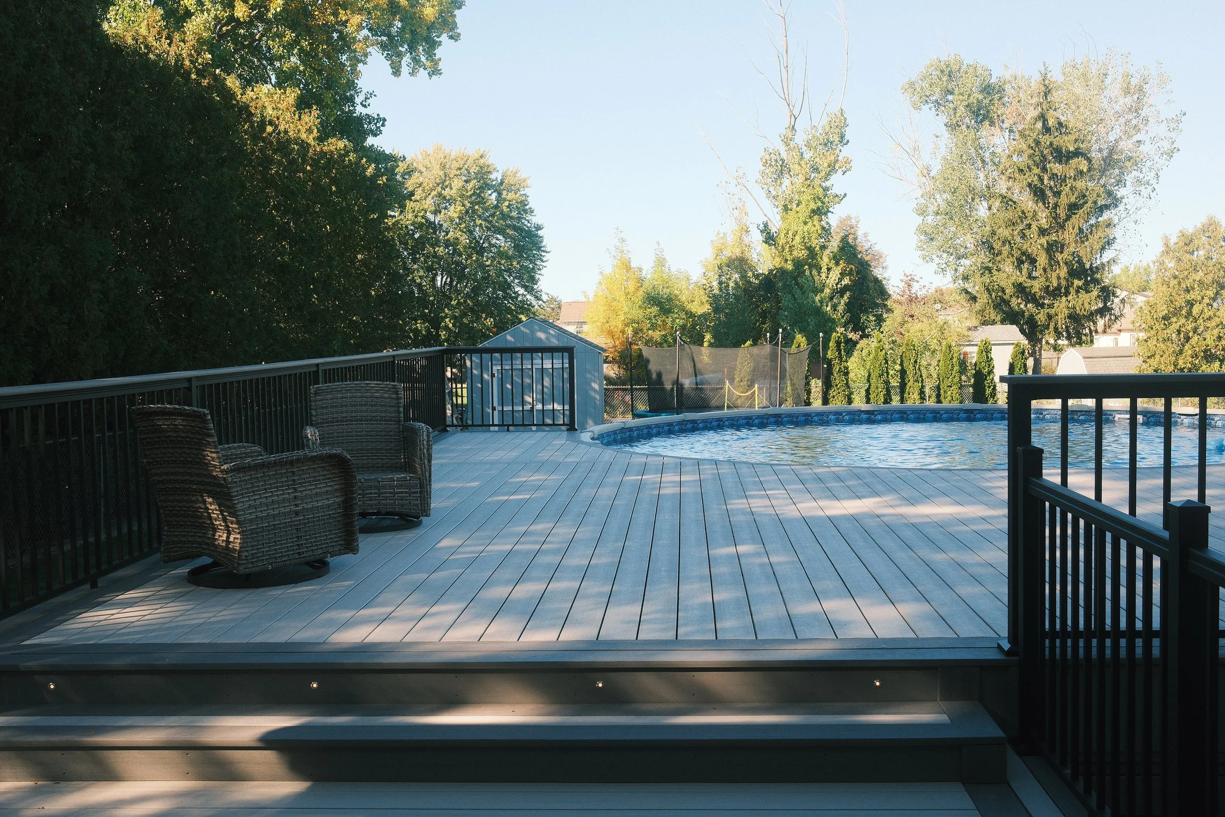 PVC backyard deck with pool and railing.