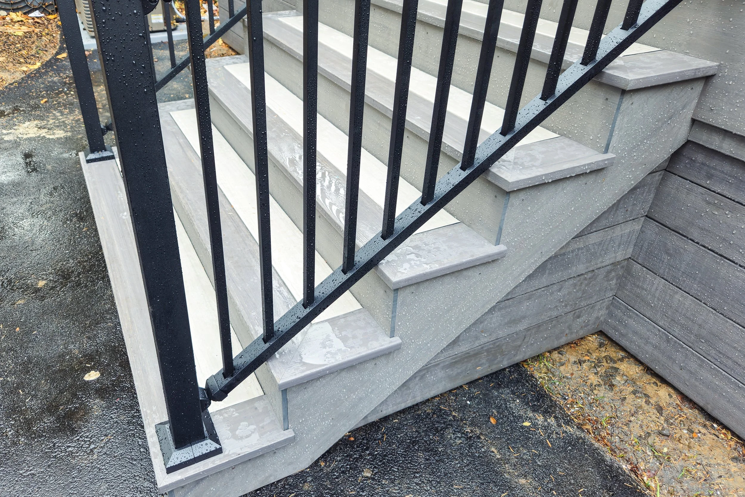 Gray deck stairs with black railing and matching fascia trim.