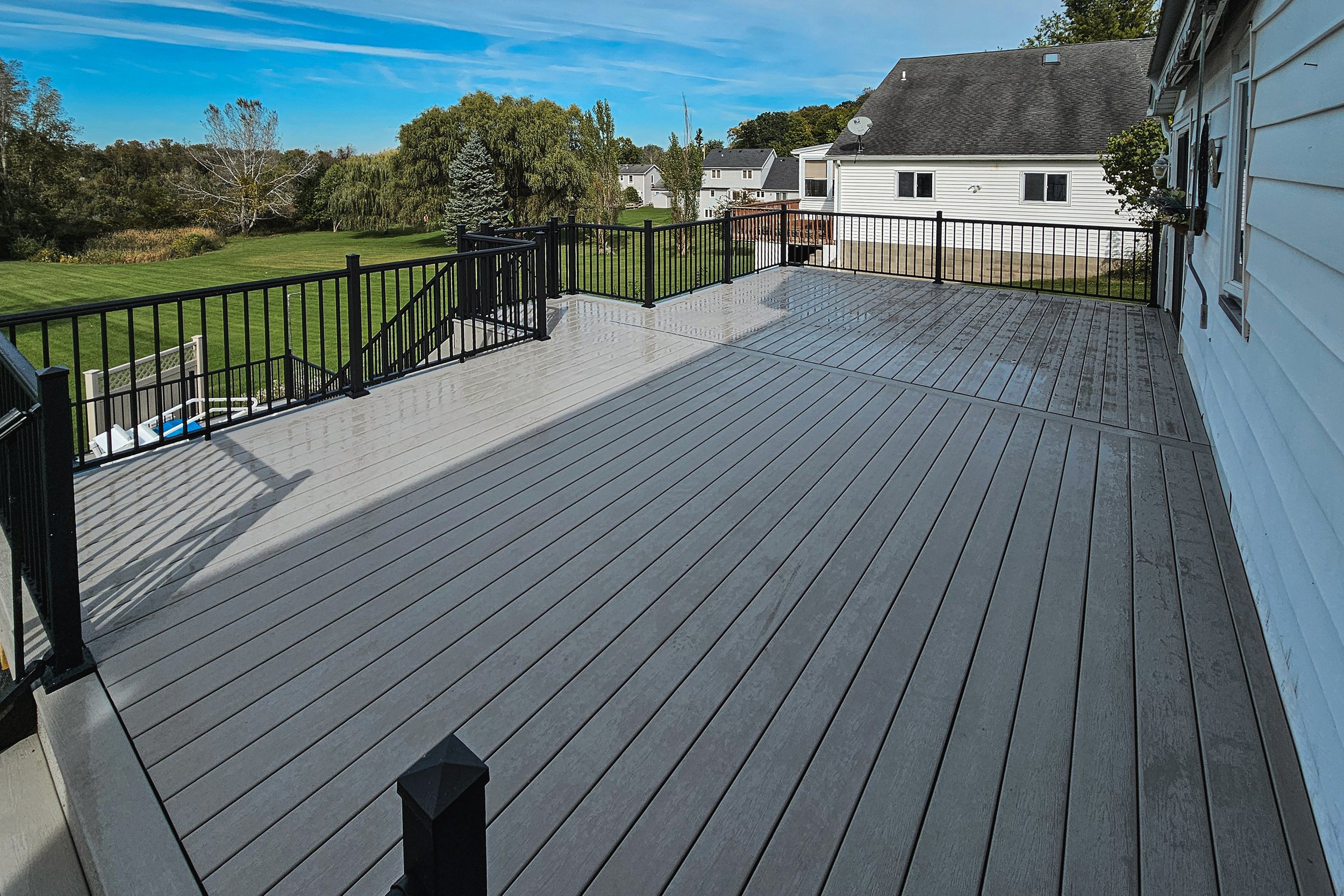 Composite deck with black railing overlooking the backyard.