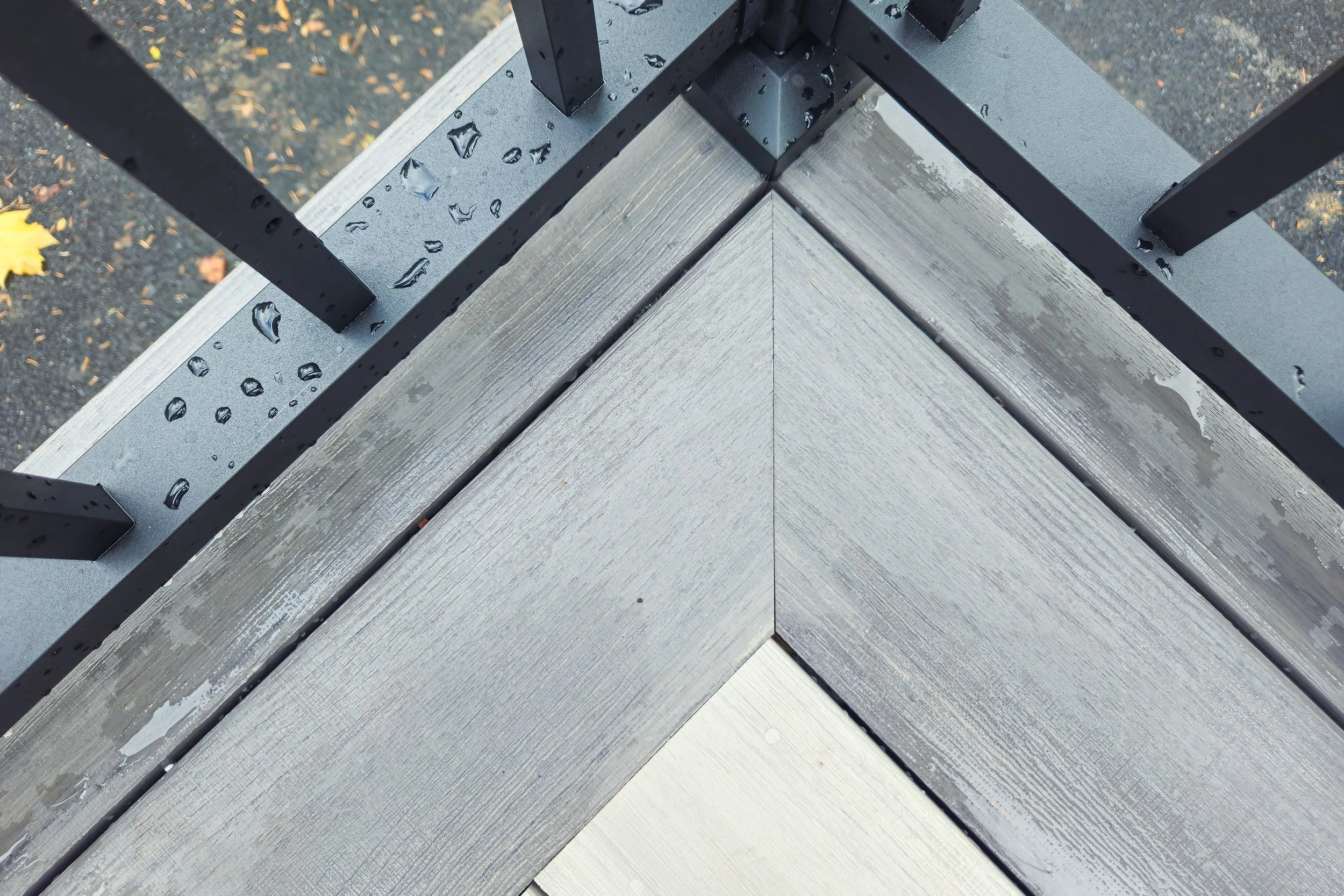 Gray PVC deck corner miter detail with black railing post.