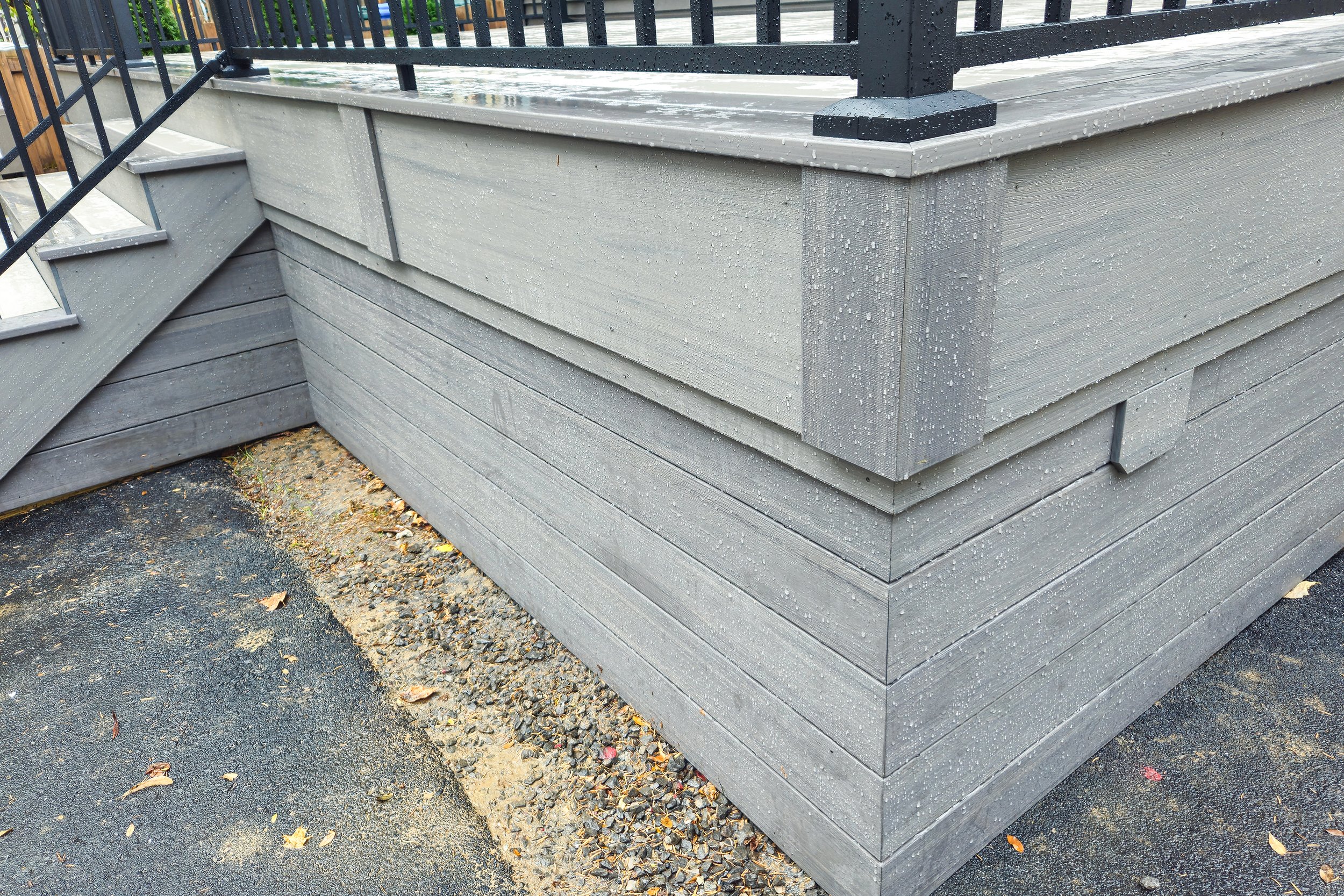 Gray PVC deck skirting with horizontal fascia and black railing.