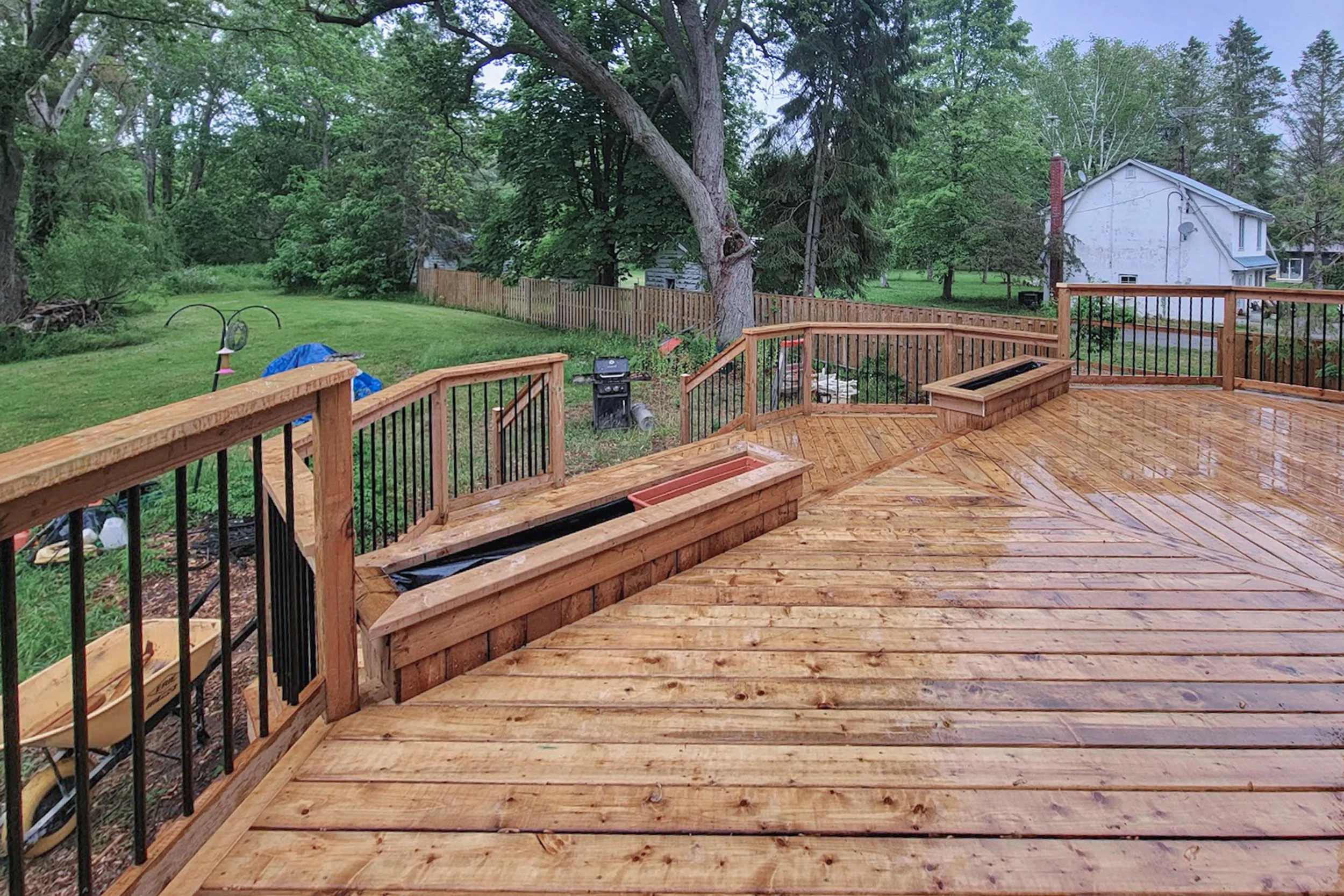 Wood deck with built-in planter bench and black railing.