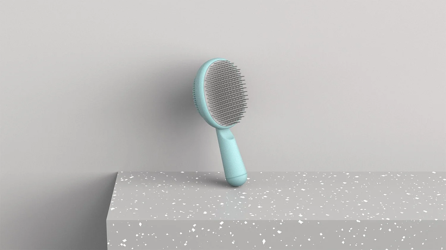 A mint green scalp massager with a handle, resting on a speckled white platform against a plain light gray background.