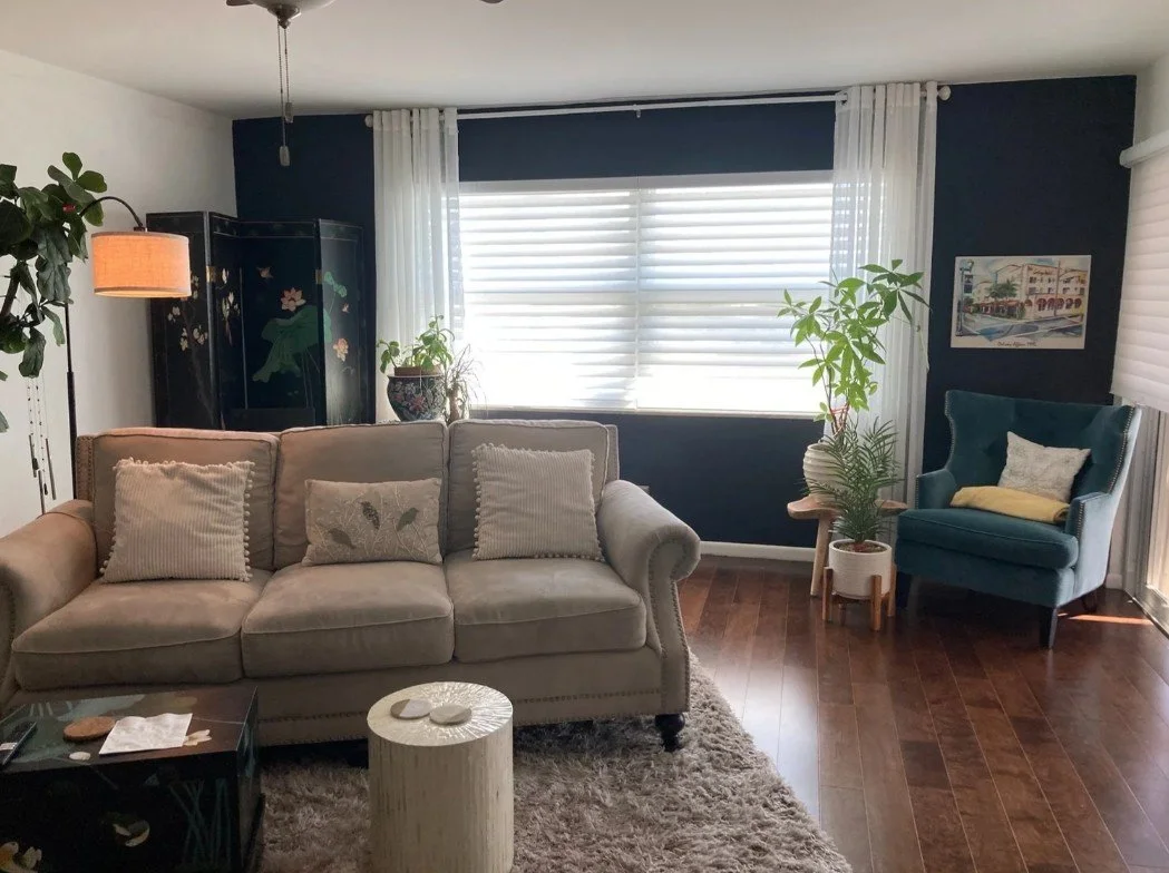 Modern living room with beige sofa, teal armchair, and white window blinds in Penfield, NY