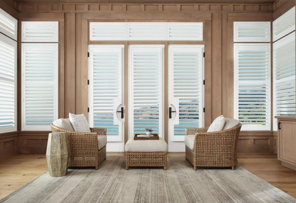 Cozy sunroom with white plantation shutters on French doors and windows, highlighting custom window blinds, shades, and shutters Fairport, NY for timeless style and light control.