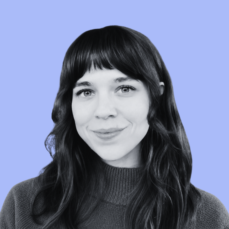 A grayscale portrait of a smiling woman with shoulder-length hair on a light blue background.