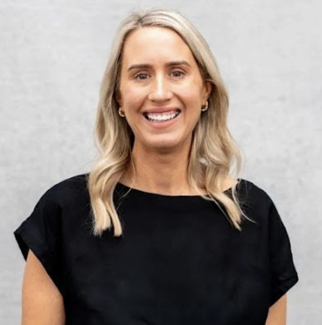 A woman with long brown hair, wearing a bright green blouse, smiling against a neutral background.