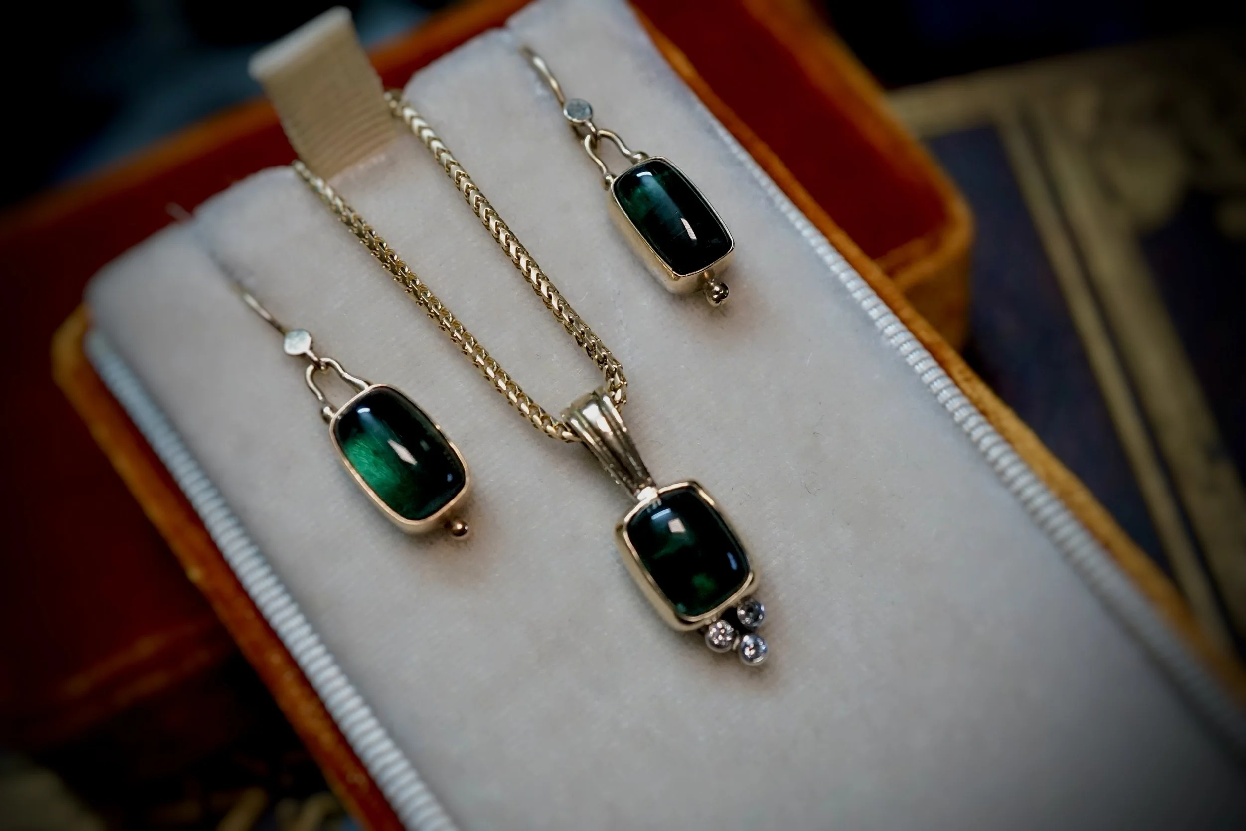 Gold necklace with a red stone pendant and a silver starfish charm placed on black textured surface.