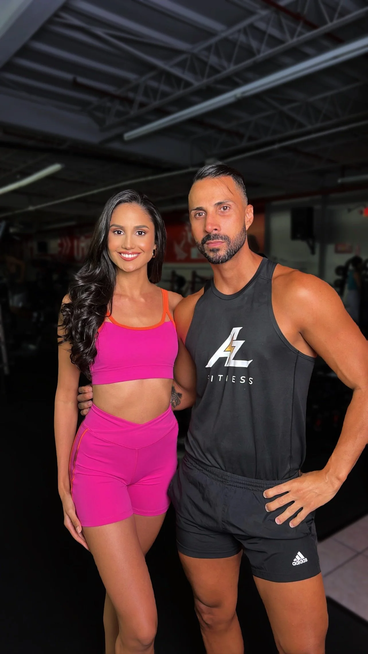 A man and woman in workout gear standing together in a gym.
