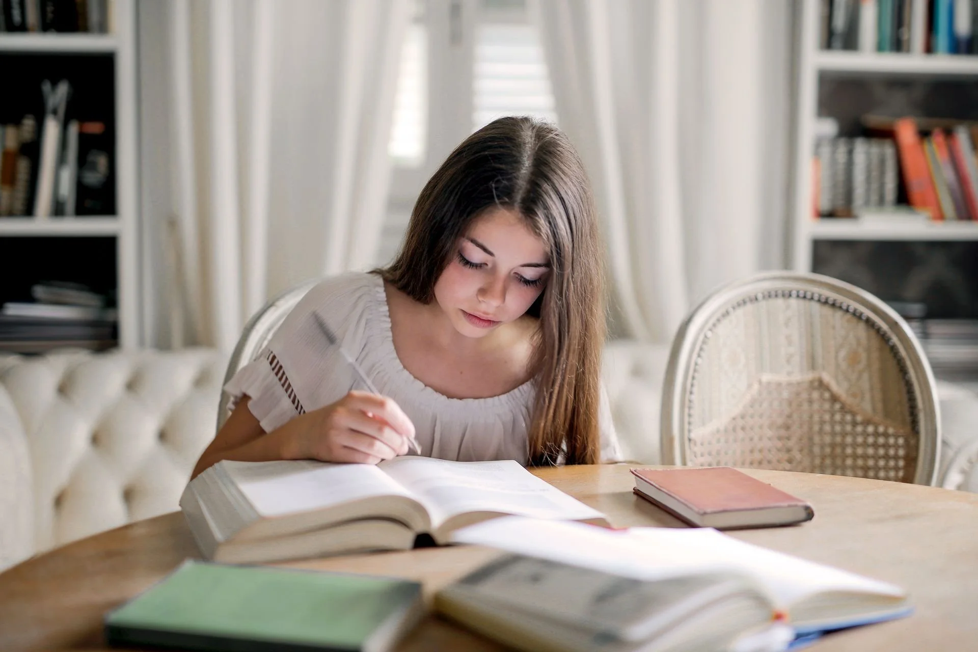 Teenage girl studying at home with books and schoolwork