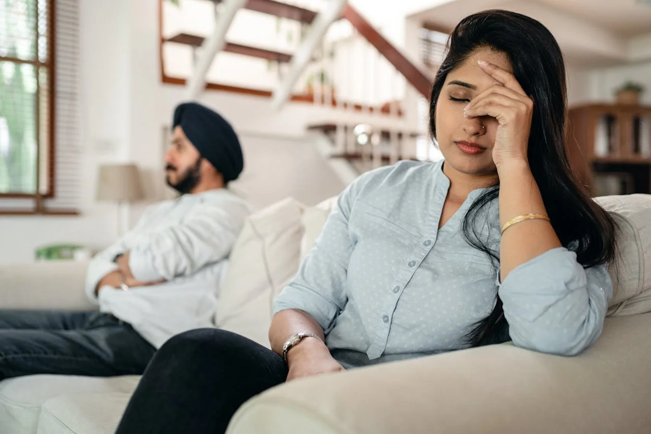 Couple sitting apart on a couch in a home setting, representing relationship counselling services in Alberta.
