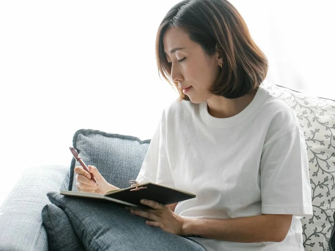 Person writing in a notebook during a therapy exercise, representing Cognitive Behavioural Therapy services in Alberta.