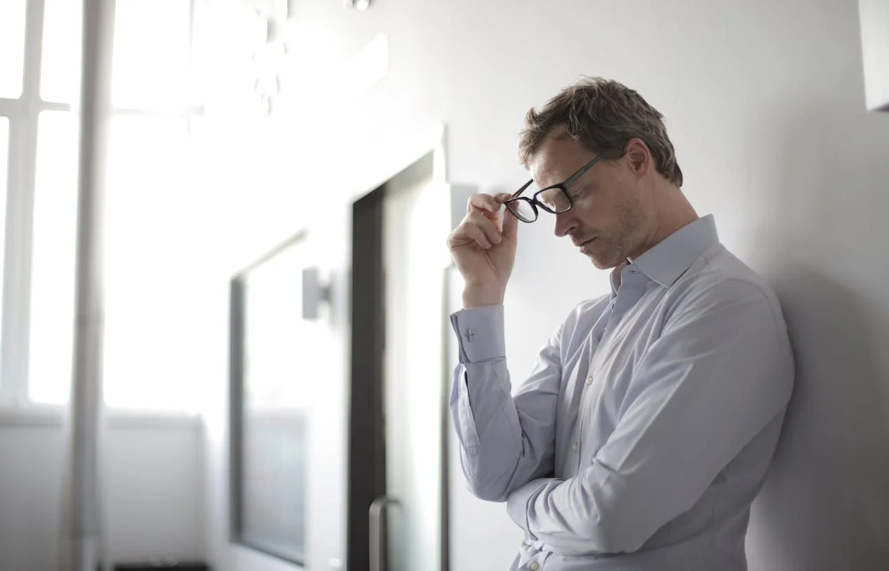 A man leaning against a wall looking down, reflecting on his behaviour after an angry episode