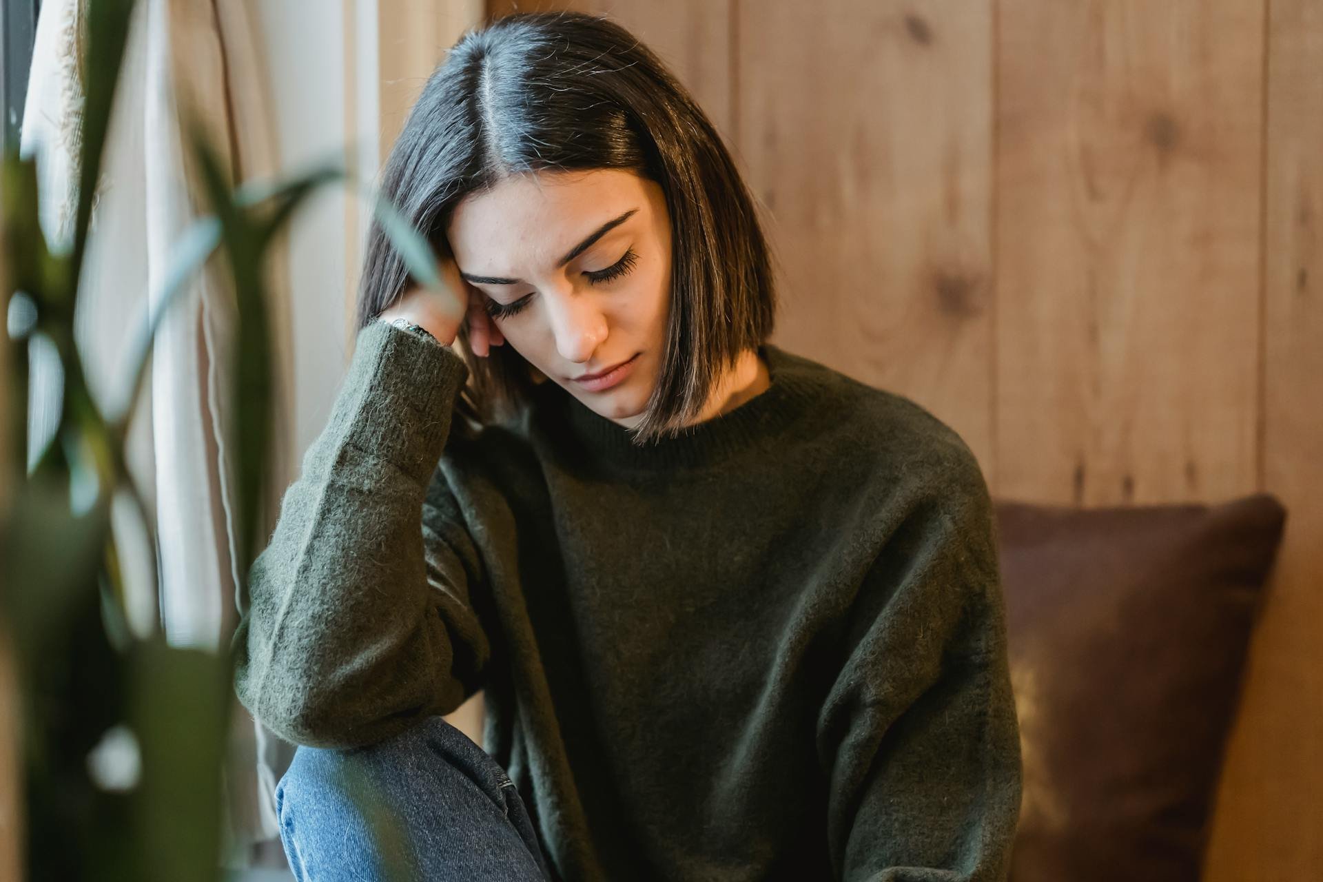 Woman sitting quietly with visible emotional exhaustion while reflecting on the effects of past trauma