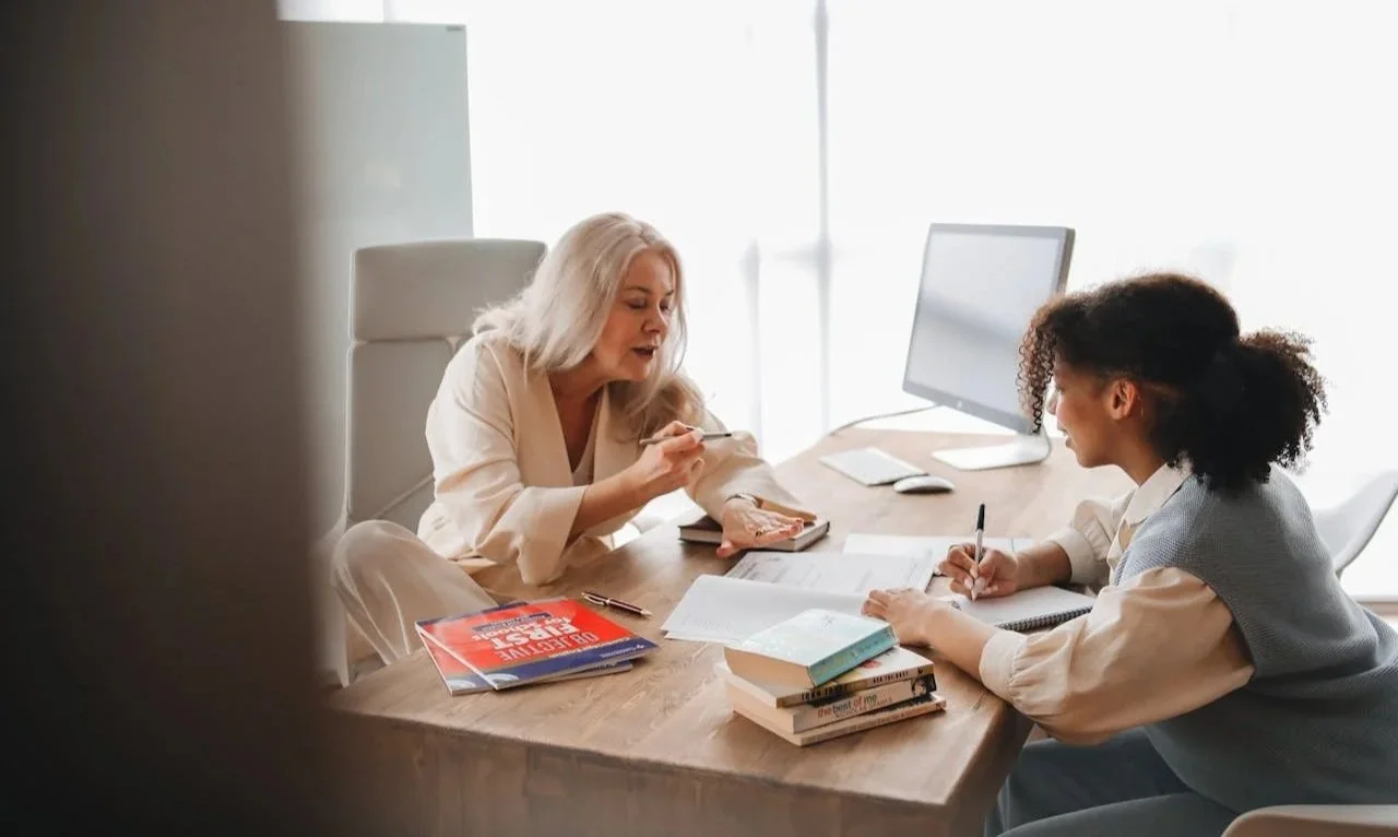 Two women reviewing notes together at a desk, representing professional life coaching services in Alberta.