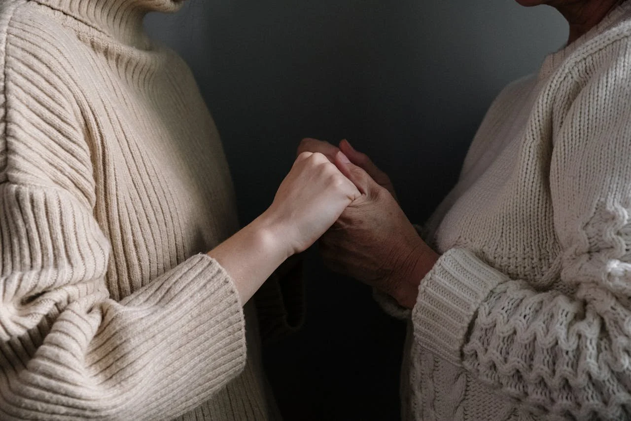 Two adults gently holding hands in soft natural light, symbolizing emotional safety, secure attachment, and supportive connection.