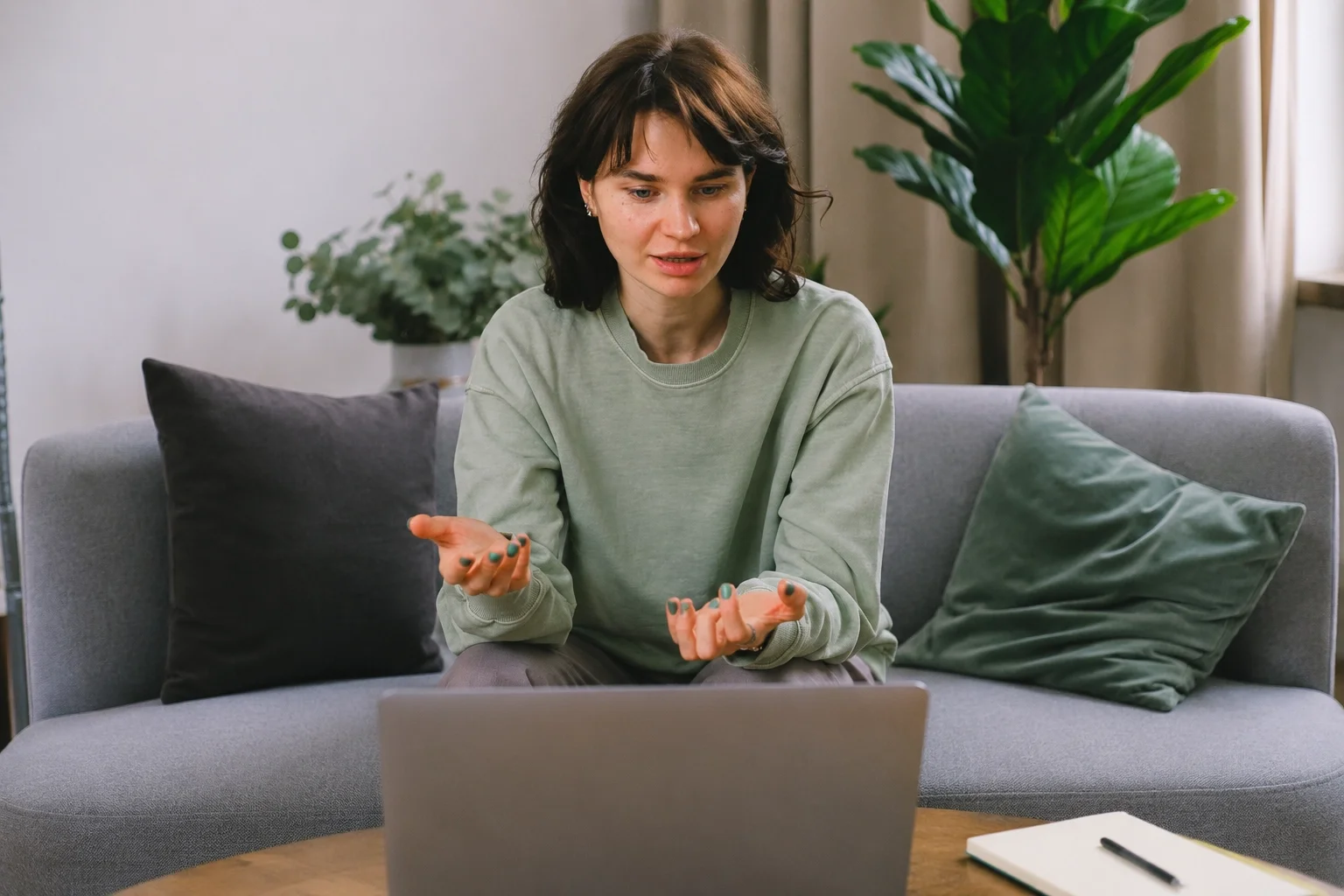 Woman speaking during an online video counselling session from home with an Alberta therapist on a laptop screen.