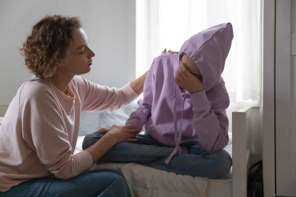 Parent comforting teenager during difficult emotional moment at home highlighting use for therapy.