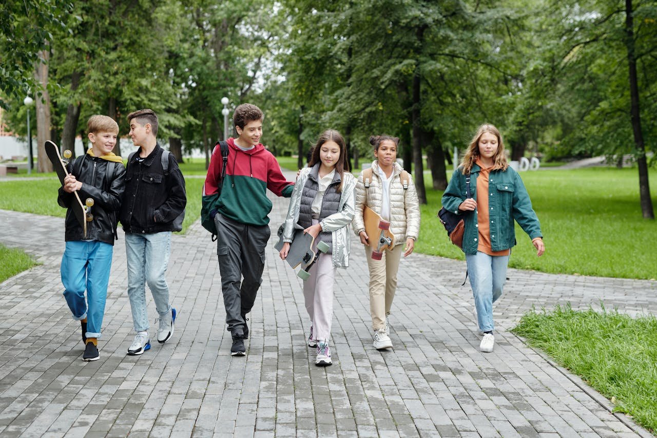A diverse group of Alberta teenagers walking together in a park, carrying skateboards and backpacks, symbolizing connection, resilience, and youth mental health support.