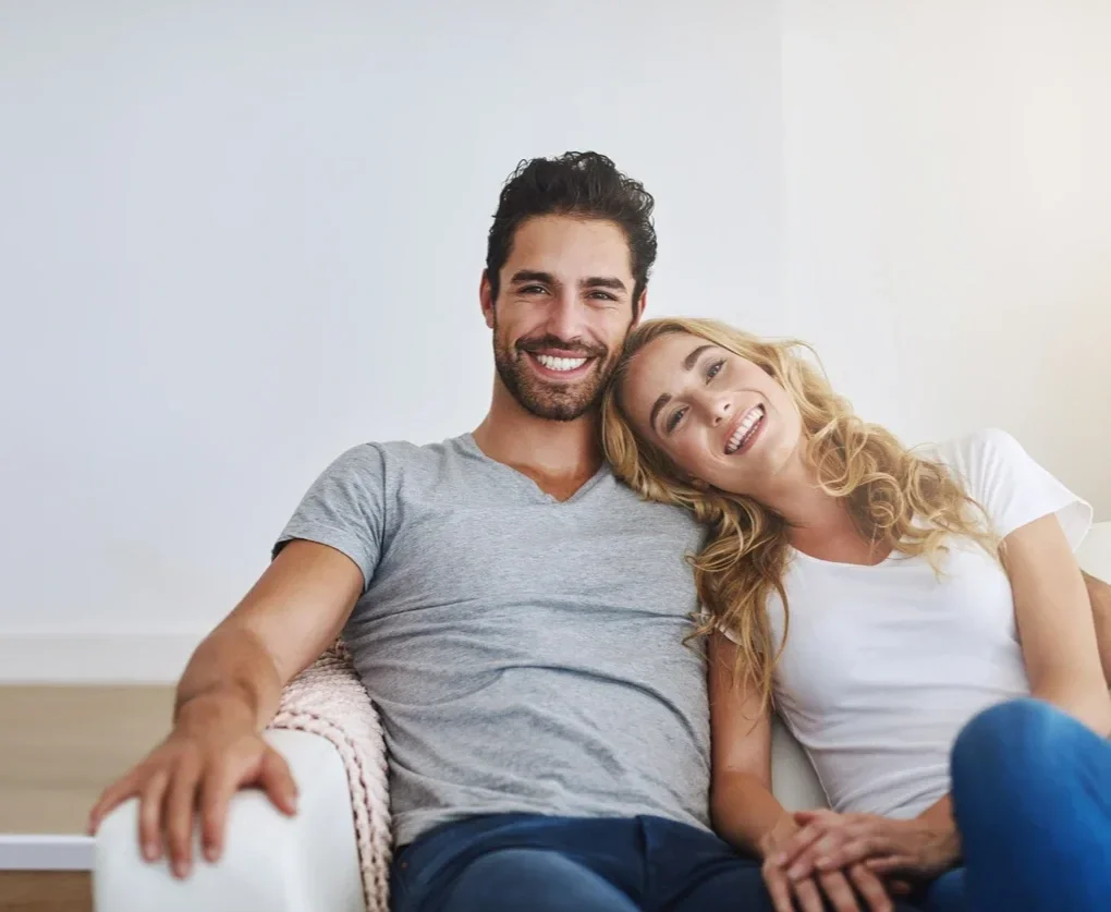 Couple sitting together on a couch in a relaxed home setting, representing couples counselling services in Alberta.