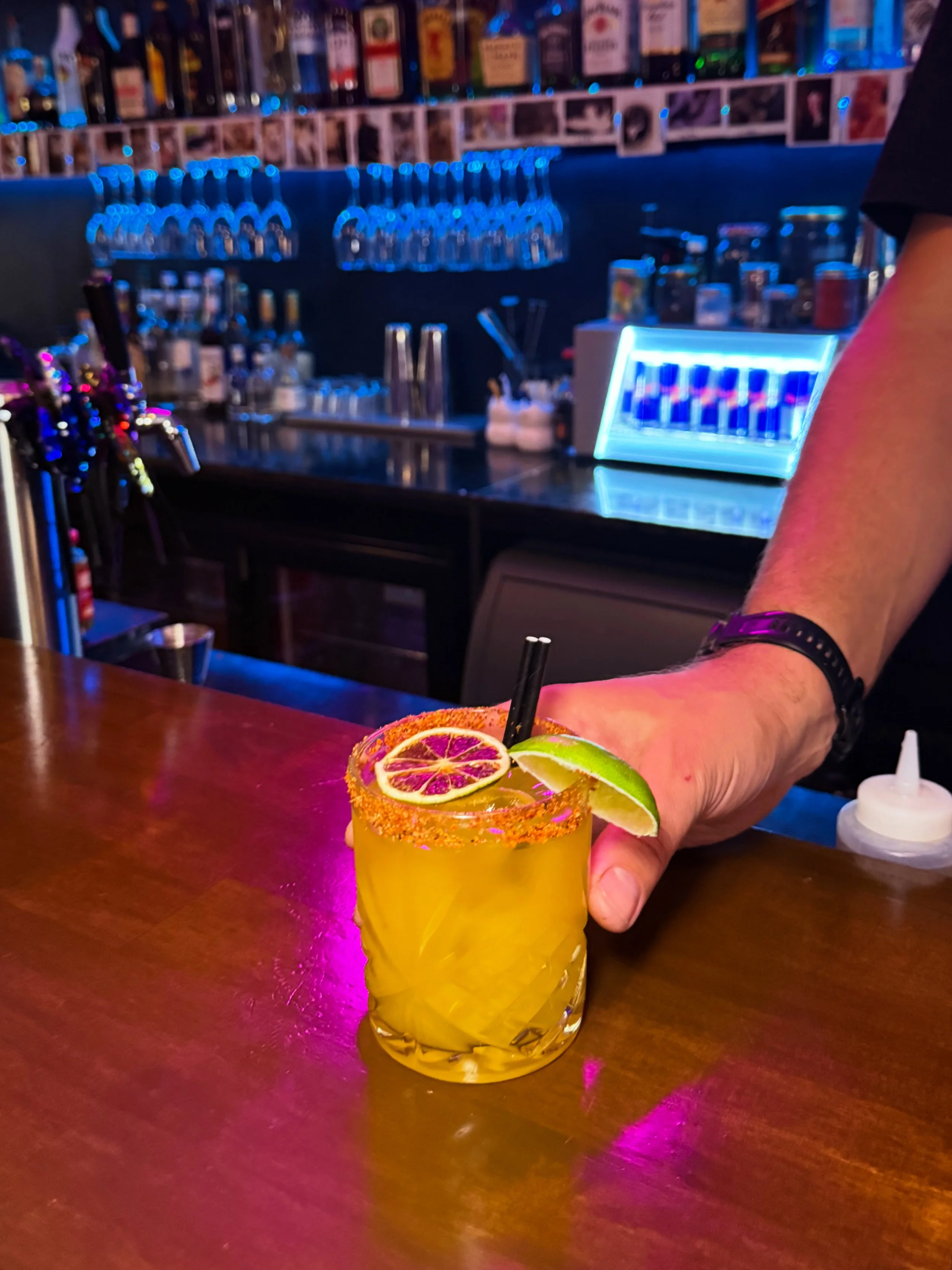 A bartender holding out a garnished spicy margarita