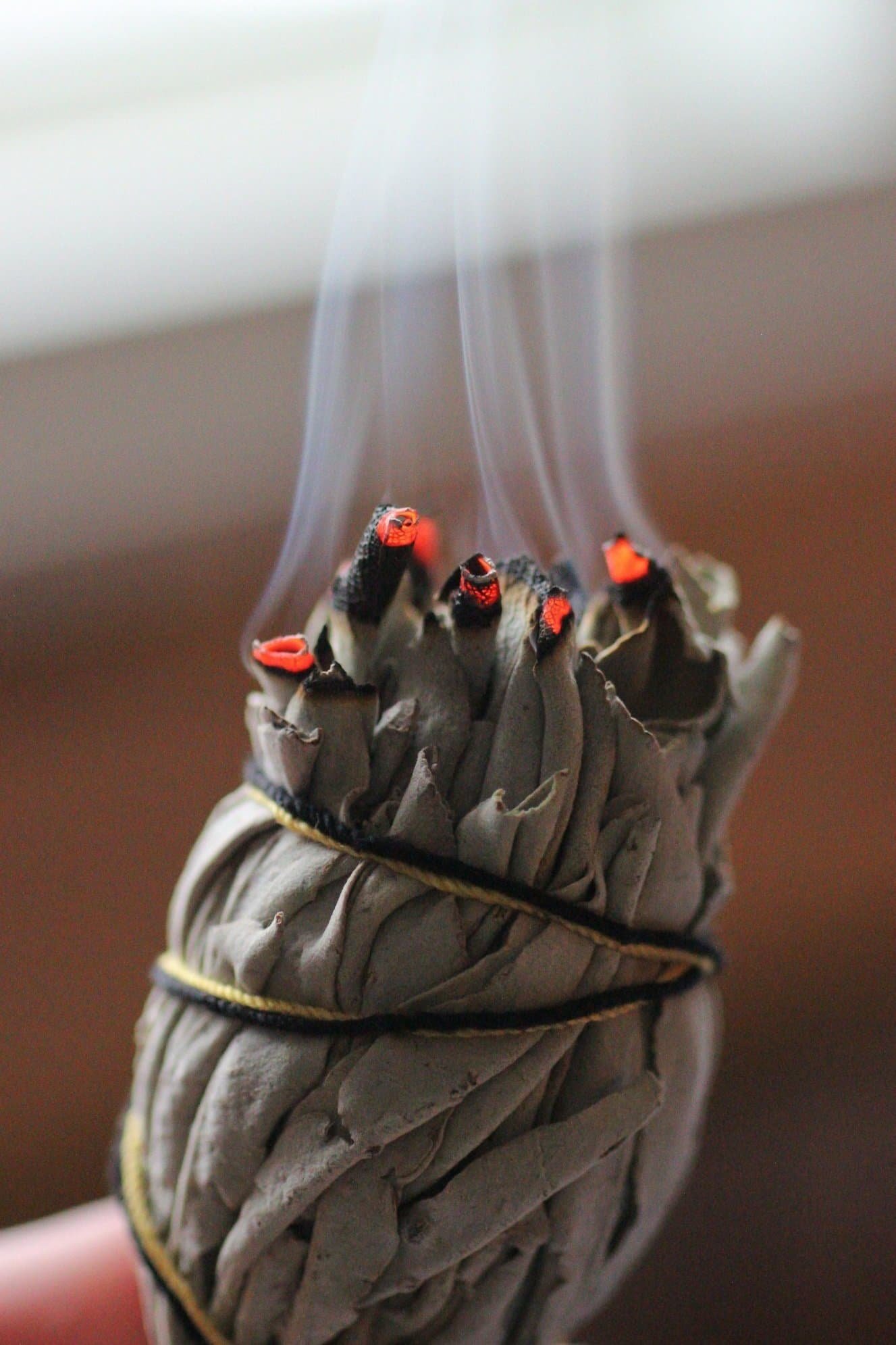 A bundle of tightly rolled sage with lit tips, producing smoke.