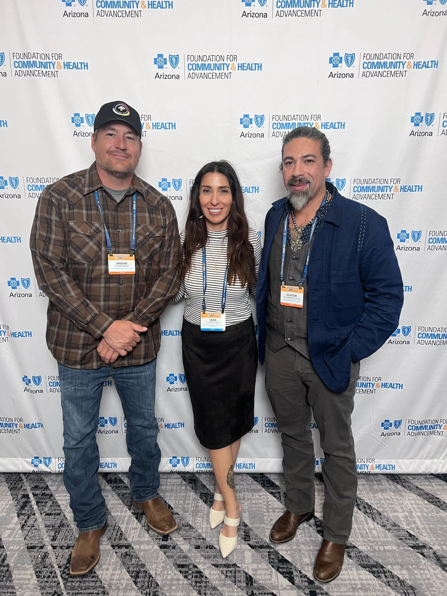 Tara Consentino, Hunter Thundercloud, and Arrow Funmaker at the Blue Cross Clue Shield State of Mind Summit in Phoenix, Arizona, standing in front of a BCBS background. 