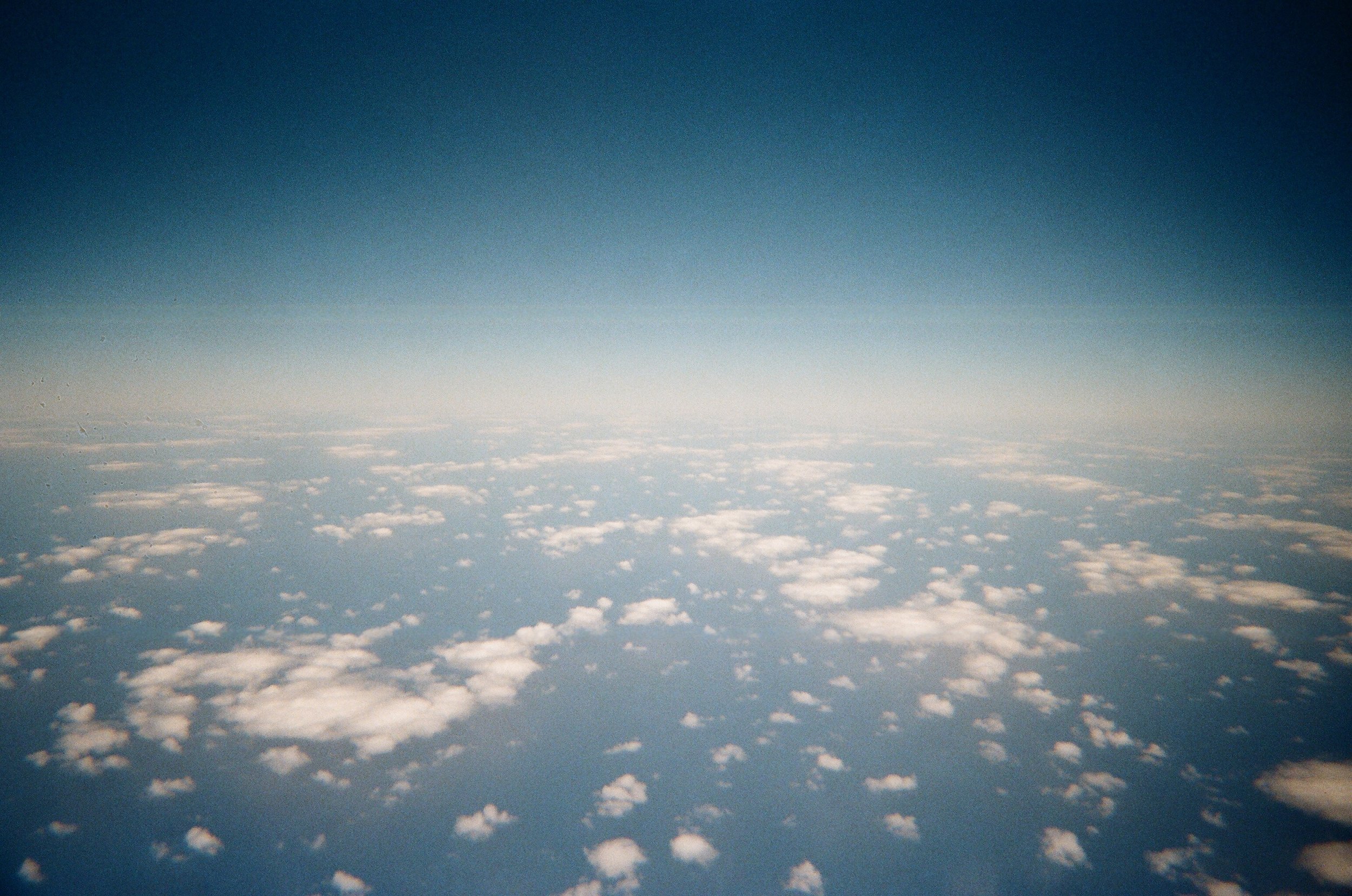 Vista dall'alto delle nuvole sopra l'atmosfera terrestre, con un gradiente di colore dal blu scuro al chiaro.