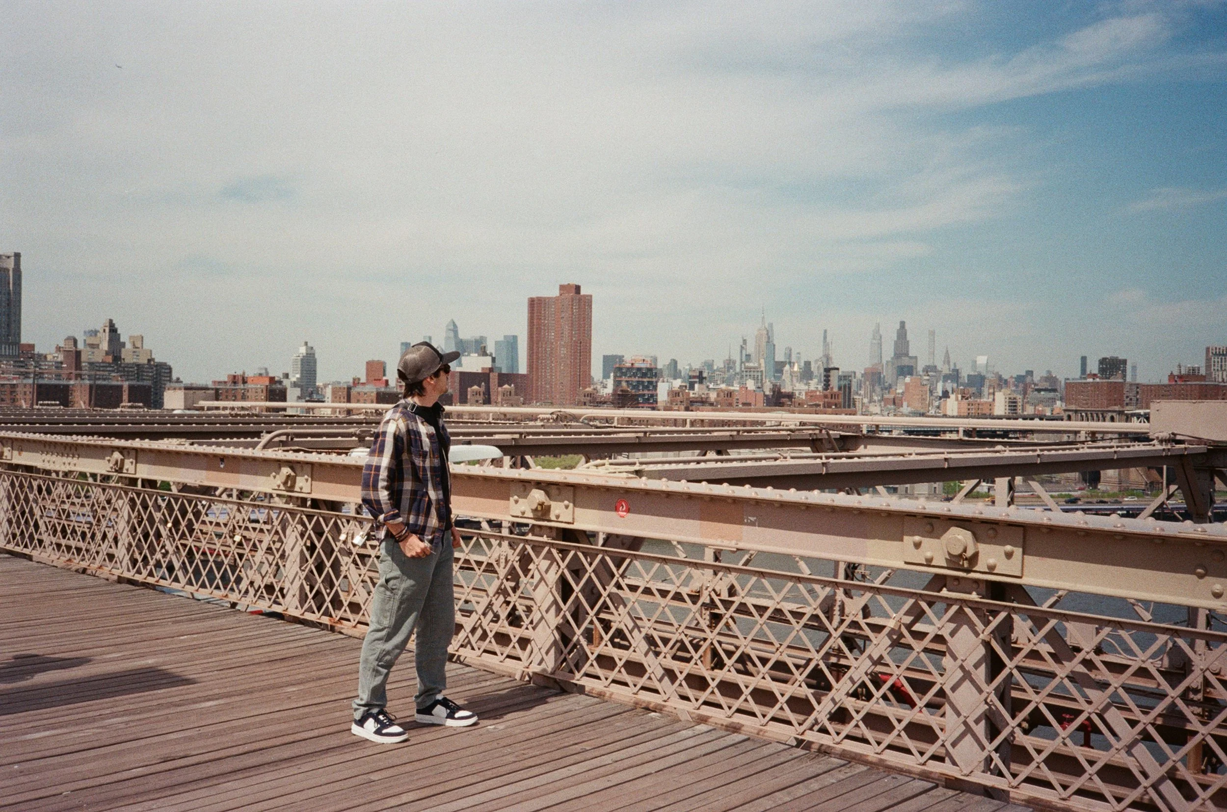 Una persona che guarda il paesaggio della città da un ponte di ferro in un giorno soleggiato.