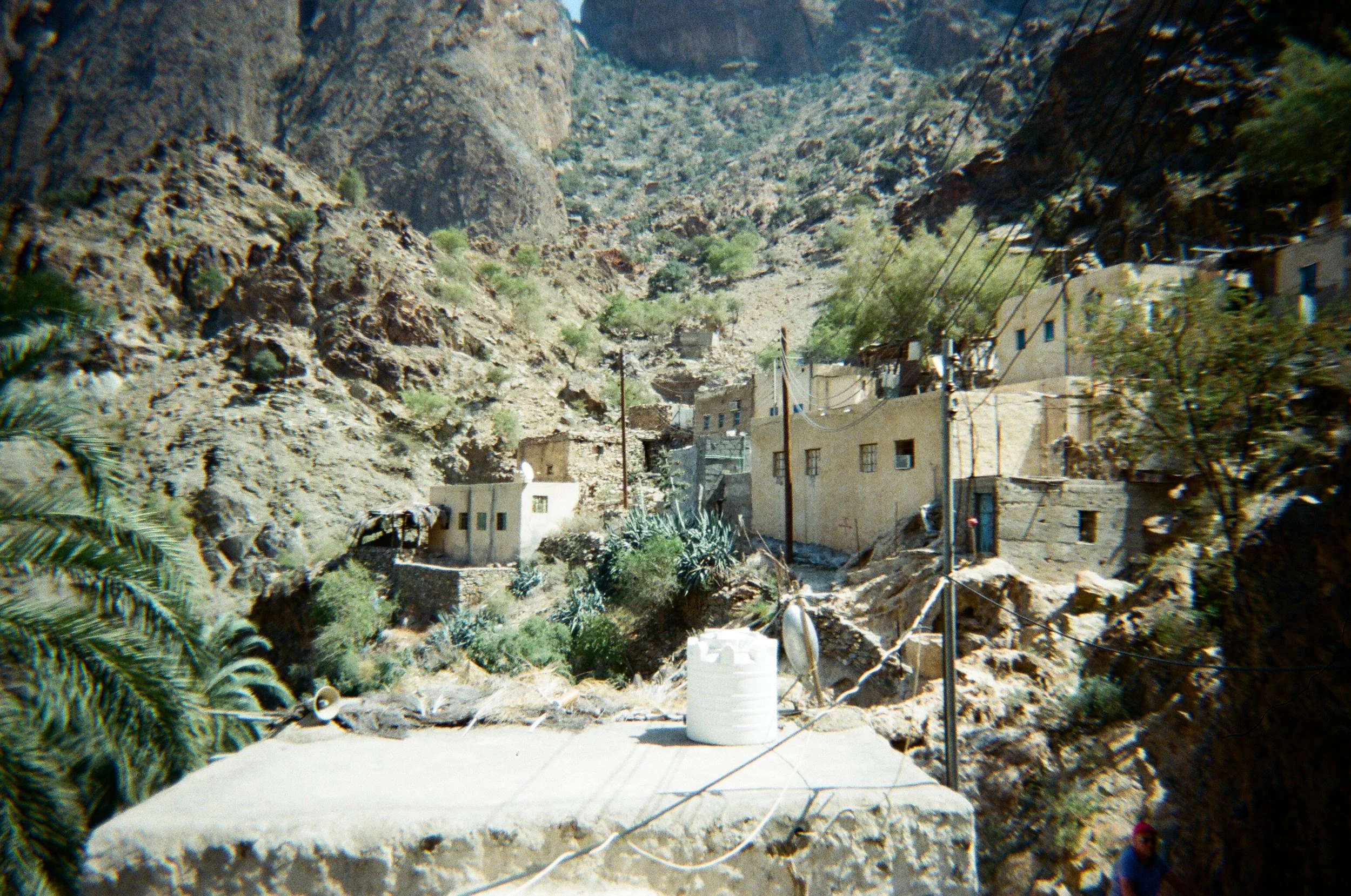 Paesaggio di un villaggio di montagna con case di pietra, reti di energia elettrica e vegetazione