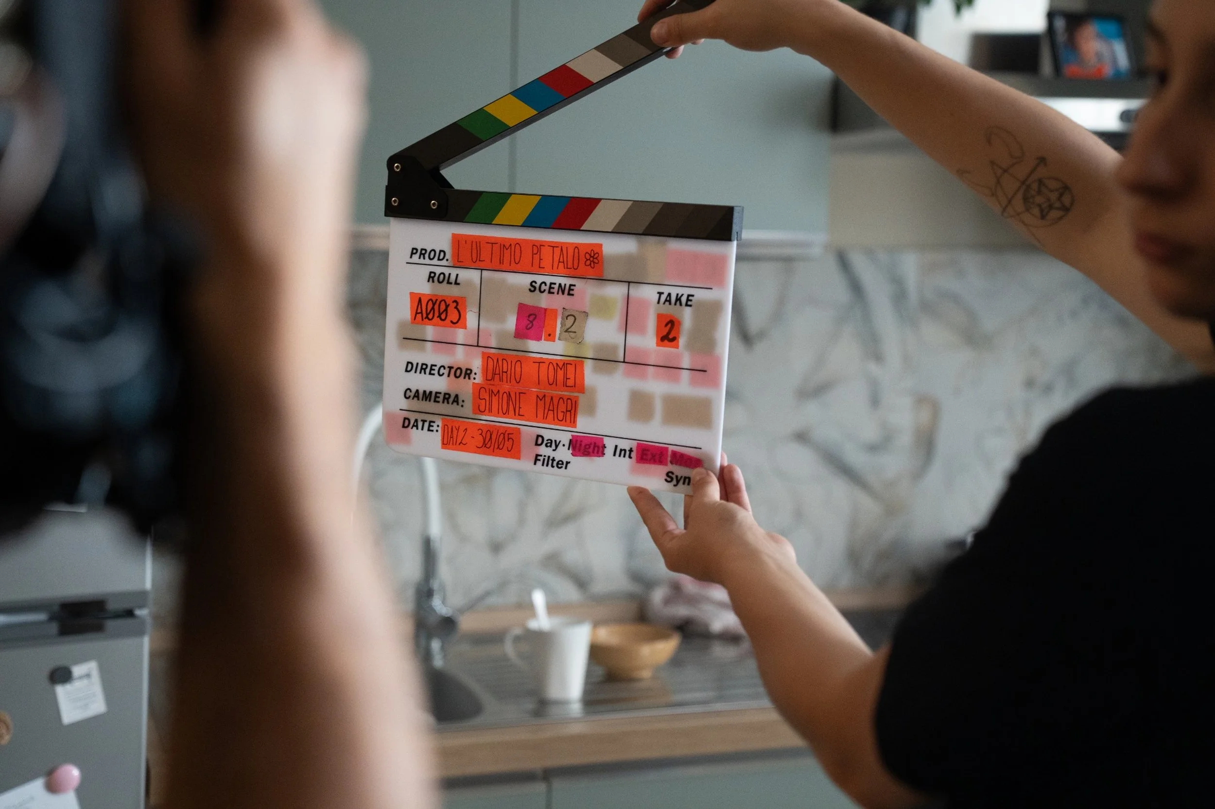 Operatore che tiene una clapperboard davanti a un set cinematografico. L'ultimo Petalo, cortometraggio di Dario Tomei girato a Milano nel 2026.