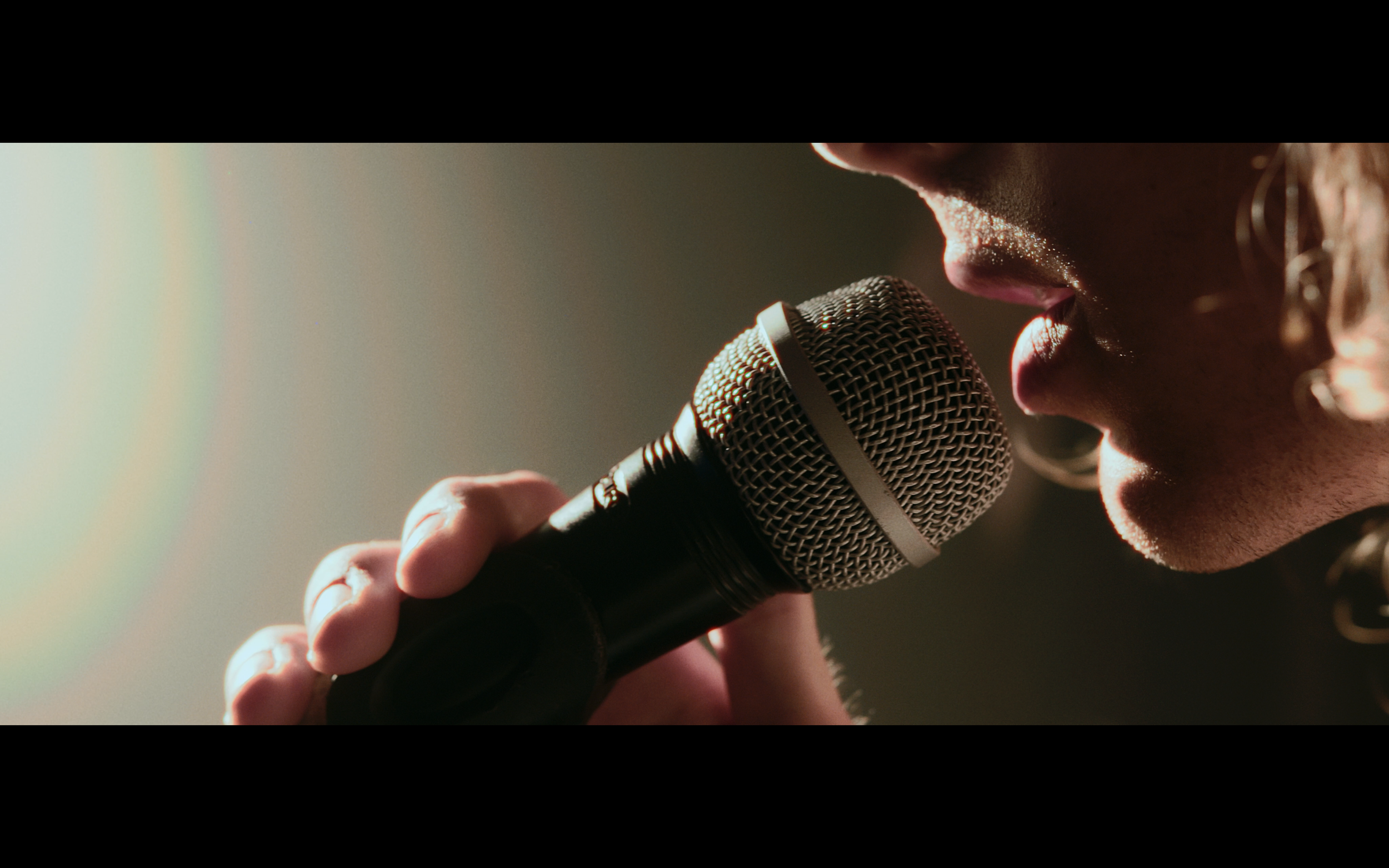 Primo piano di una persona che tiene un microfono vicino alle labbra.