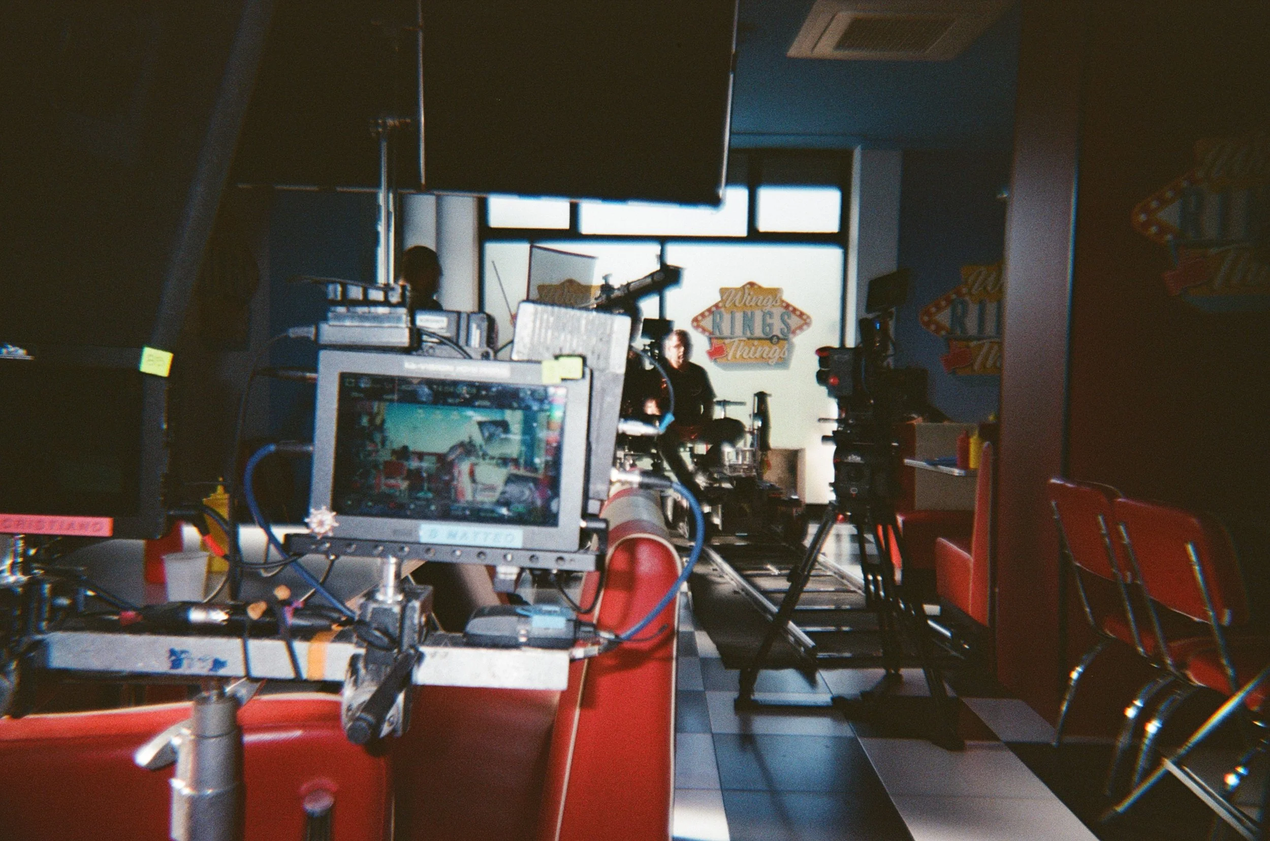 Set cinematografico in una sala di editing con monitor e attrezzature, pareti decorate con insegne colorate e sedie rosse