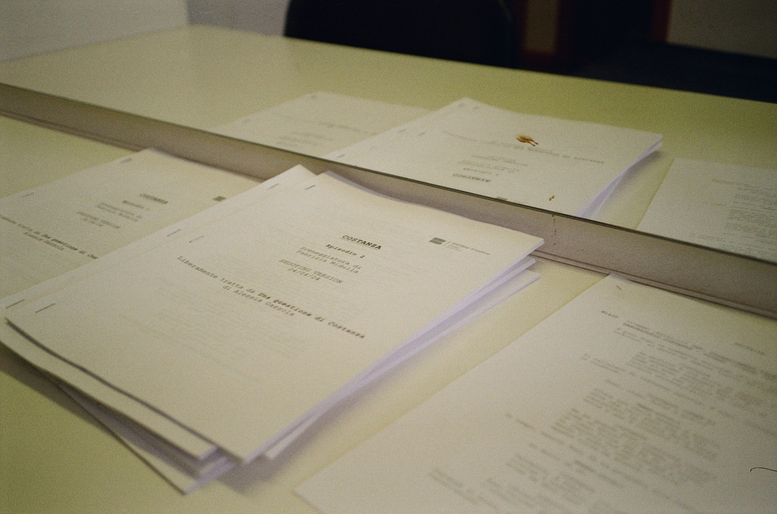 Documenti e fogli di carta disposti su una scrivania con uno specchio posizionato sopra