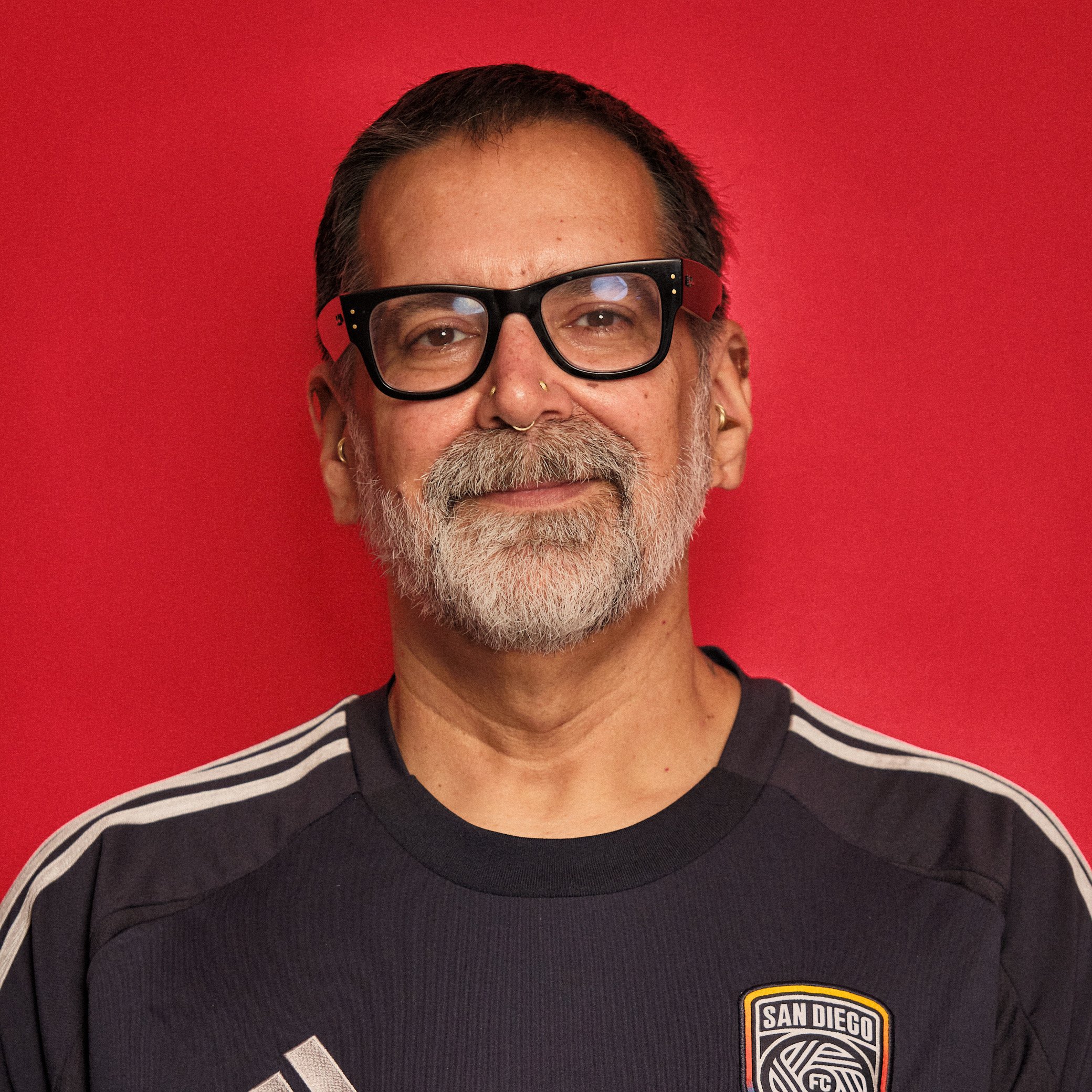 Didier Suarez, owner of Enigma Professional Piercing Studios in San Diego, wearing glasses and showcasing his nose piercing