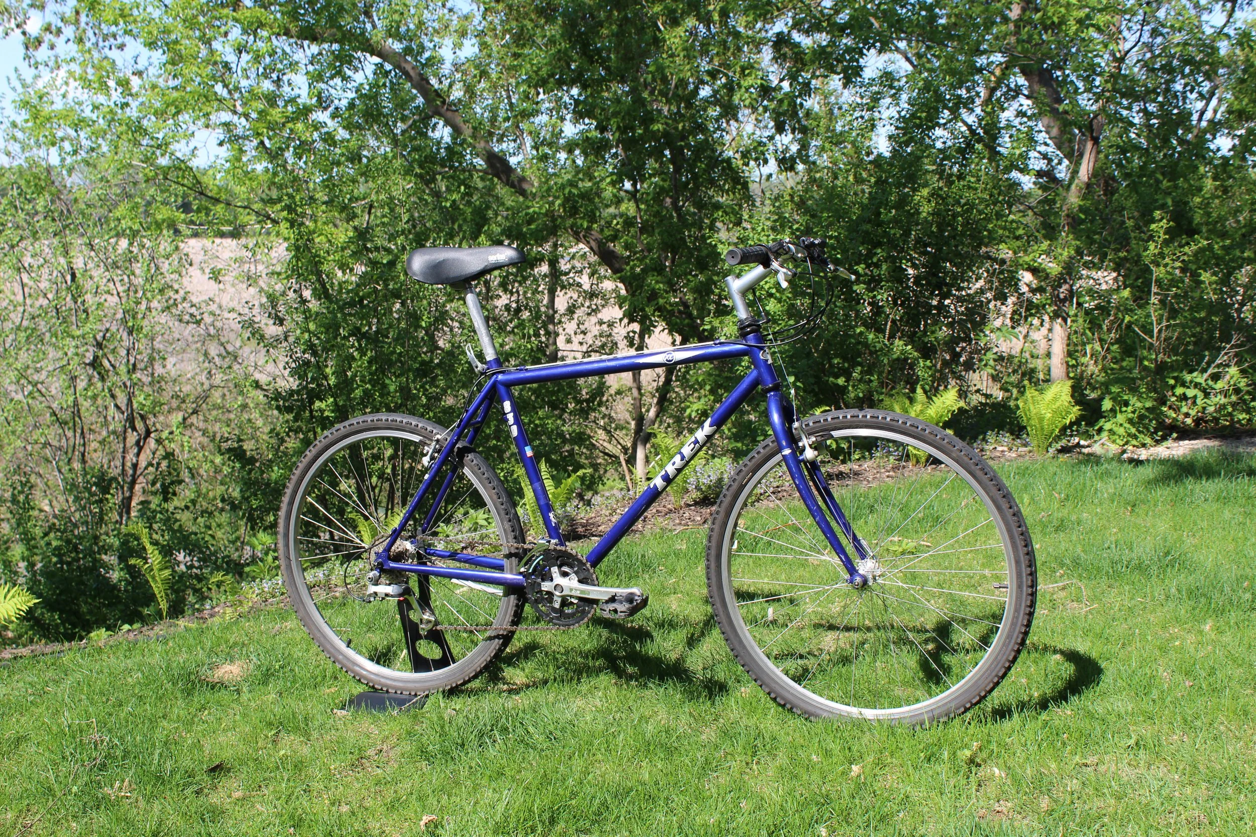Blue mountain bike on grass with trees in background