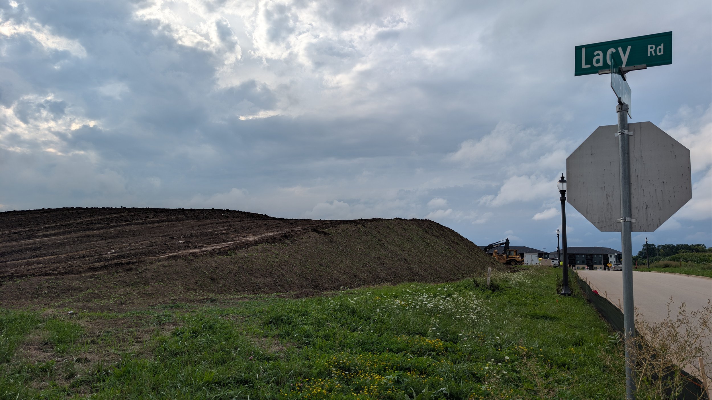 A large pile of dirt sits near a street corner