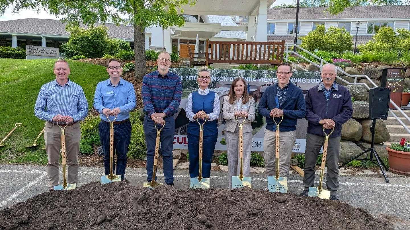 Seven people stand holding shovels