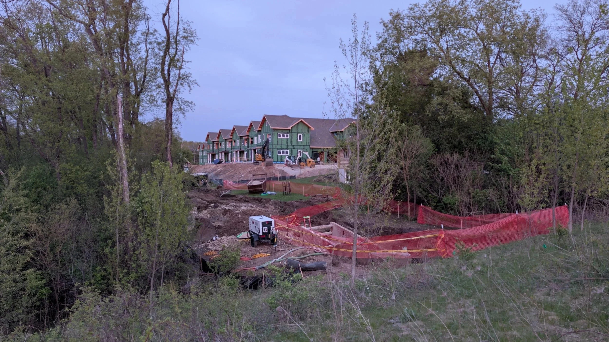 construction equipment and orange fencing in a clearing