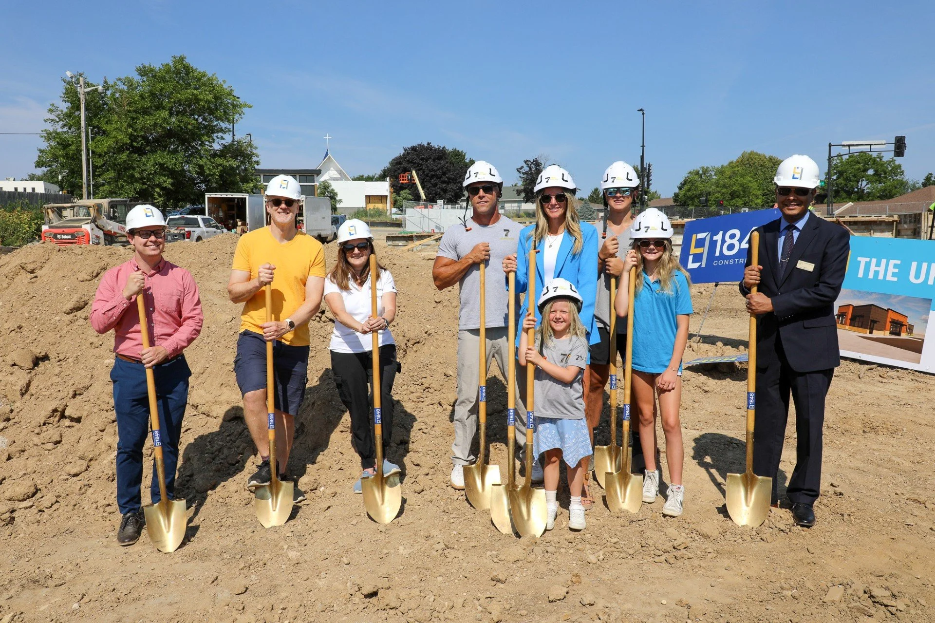 People stand with shovels at a construction site