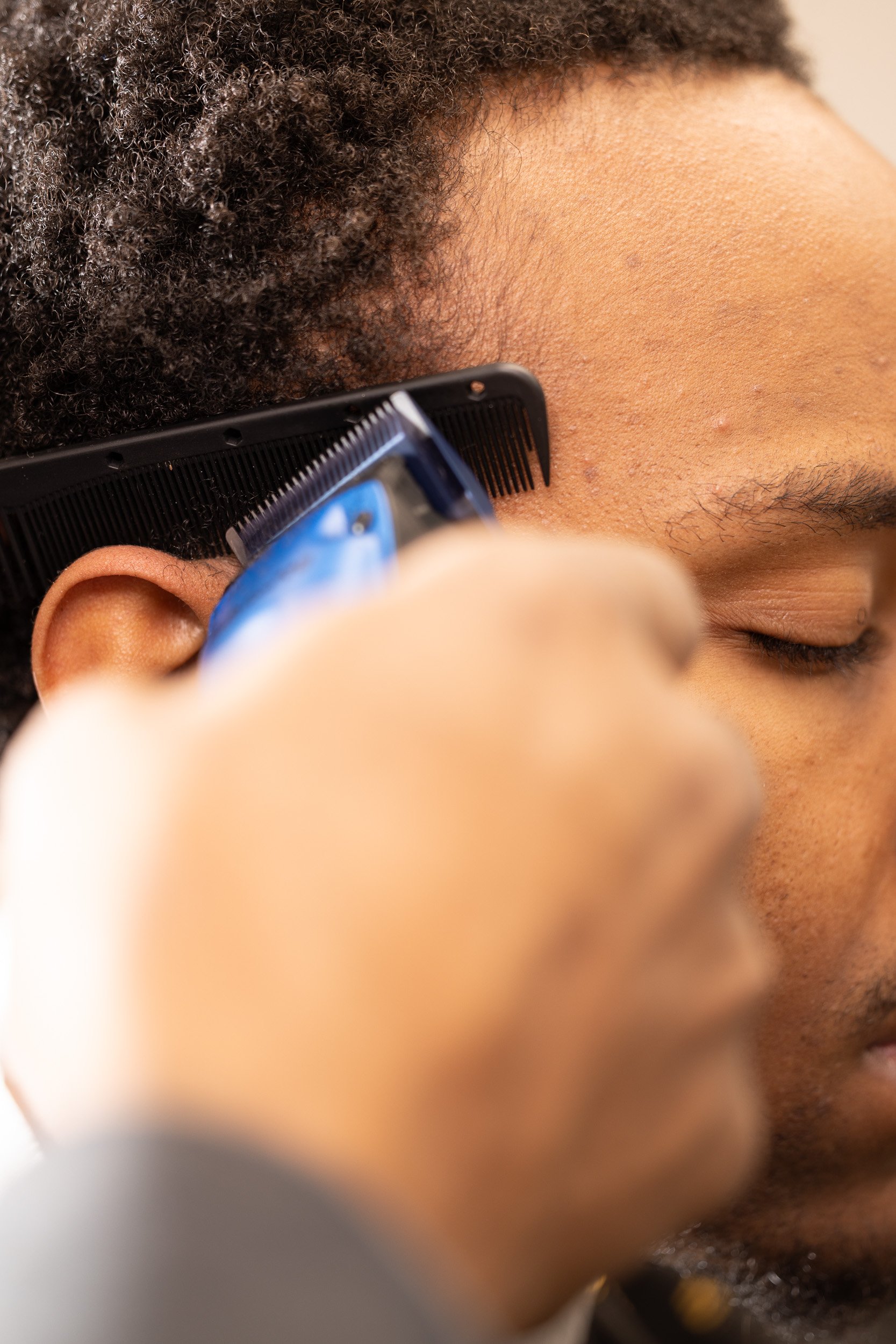 Close-up of a man getting a haircut with clippers, focusing on his face and hair.