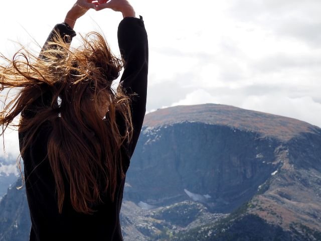 woman standing on mountain challenging the wind