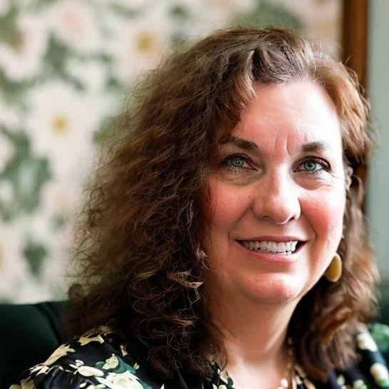 Smiling woman with curly brown hair, wearing a floral top and earrings, with a floral patterned background.